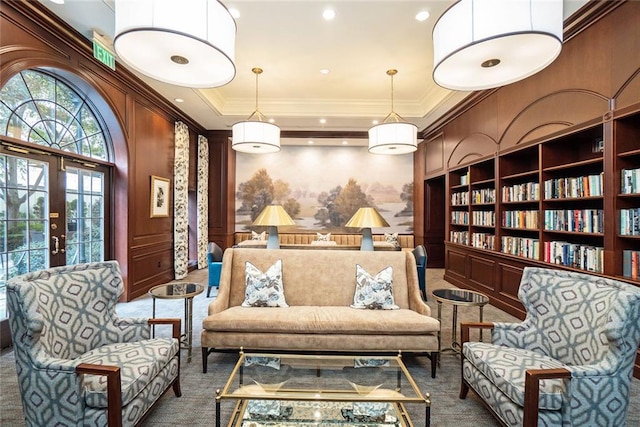 living area with a tray ceiling, built in features, ornamental molding, and carpet flooring