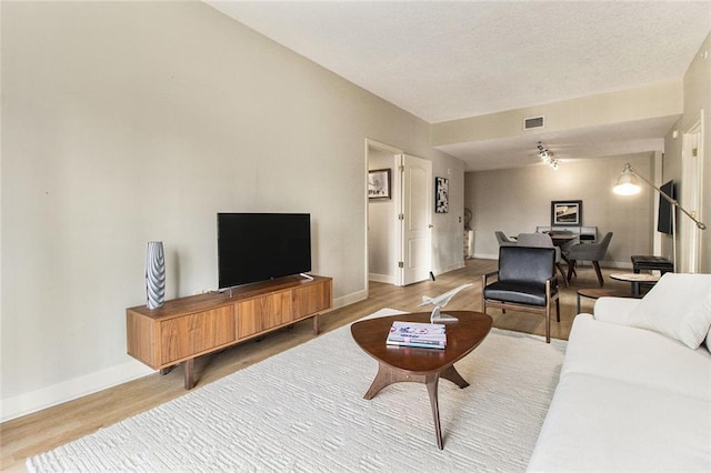 living room with visible vents, baseboards, and wood finished floors