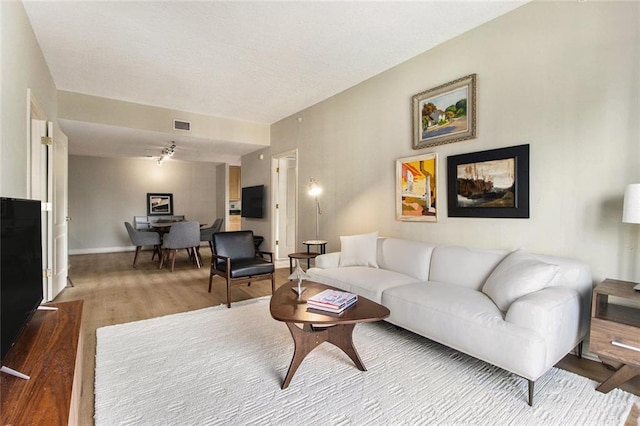 living area featuring baseboards, visible vents, and wood finished floors