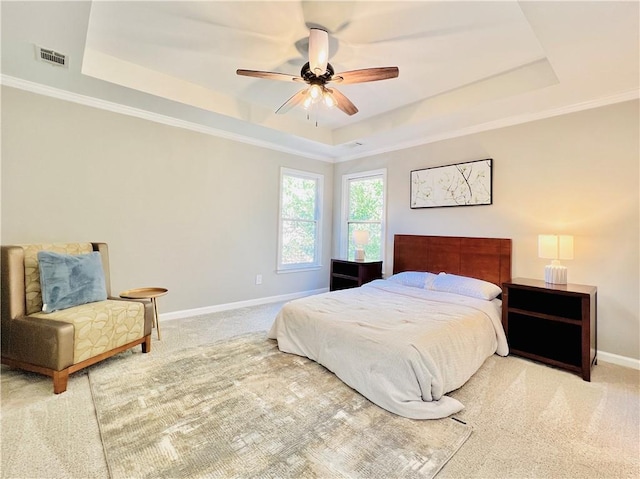 carpeted bedroom with ornamental molding, ceiling fan, and a raised ceiling