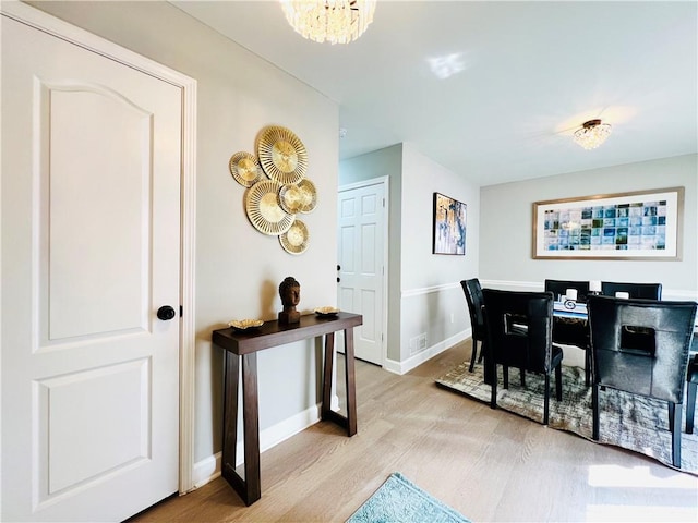 dining space with light hardwood / wood-style flooring and a chandelier