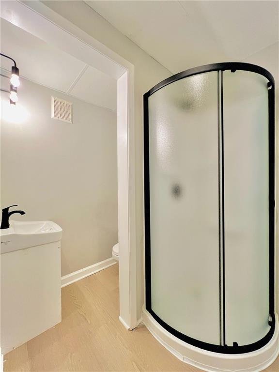 bathroom featuring vanity, hardwood / wood-style floors, toilet, and walk in shower