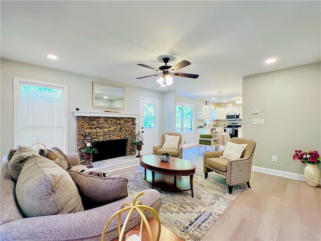 living room with ceiling fan, light wood-type flooring, and a fireplace