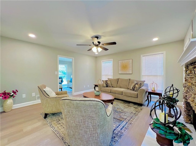 living room with light hardwood / wood-style flooring, a fireplace, and ceiling fan