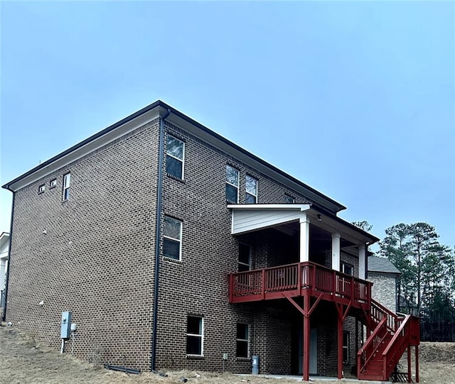 back of property featuring a deck, brick siding, and stairway