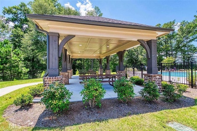 view of community featuring a patio, a swimming pool, and fence