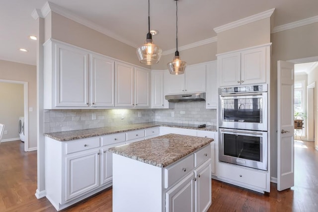 kitchen featuring under cabinet range hood, double oven, white cabinets, and dark wood-style flooring