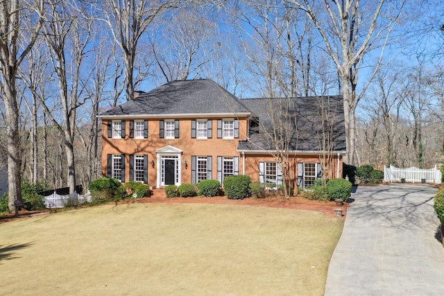 view of front of property featuring a shingled roof, concrete driveway, a front lawn, and fence