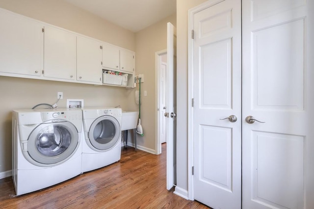 washroom featuring light wood finished floors, cabinet space, washer and dryer, and baseboards