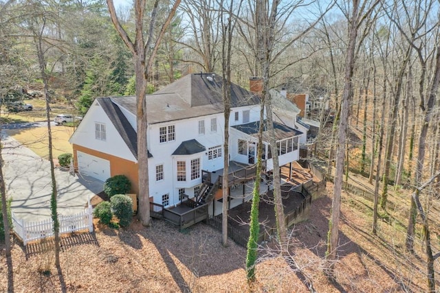 back of property featuring a shingled roof, fence, a wooden deck, a chimney, and a garage