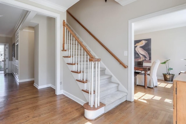 stairway featuring crown molding, wood finished floors, and baseboards