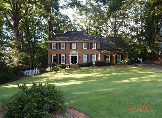 colonial home featuring a front yard and fence