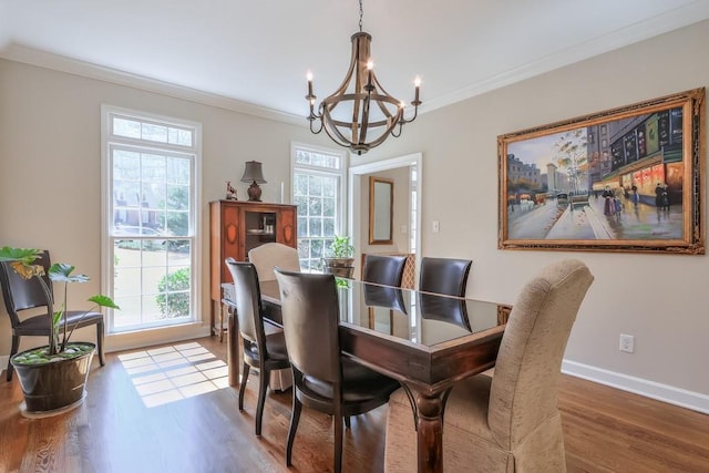 dining space featuring a notable chandelier, wood finished floors, a wealth of natural light, and ornamental molding