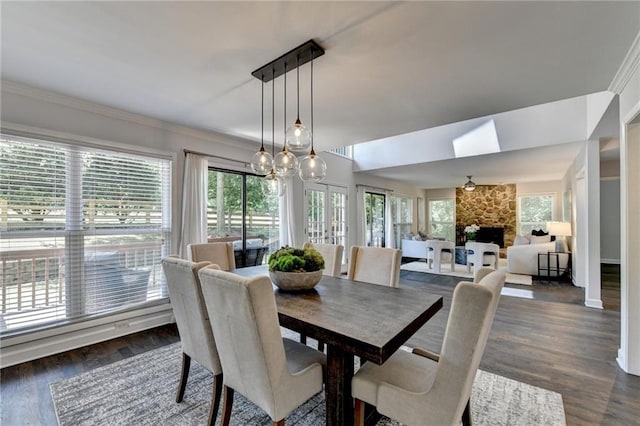 945 Tiber Cir, Alpharetta, GA 30022 - dining area featuring a stone fireplace, dark wood-style flooring, a skylight, and crown molding