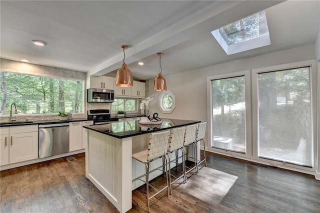 945 Tiber Cir, Alpharetta, GA 30022 - kitchen featuring stainless steel appliances, dark countertops, a sink, a kitchen breakfast bar, and white cabinetry