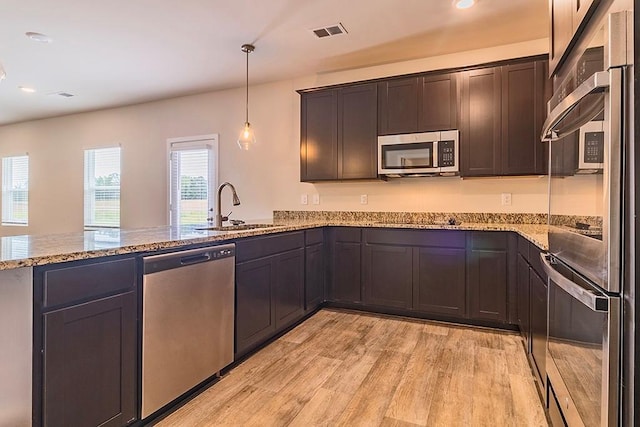 kitchen with visible vents, appliances with stainless steel finishes, light wood-style floors, a sink, and a peninsula