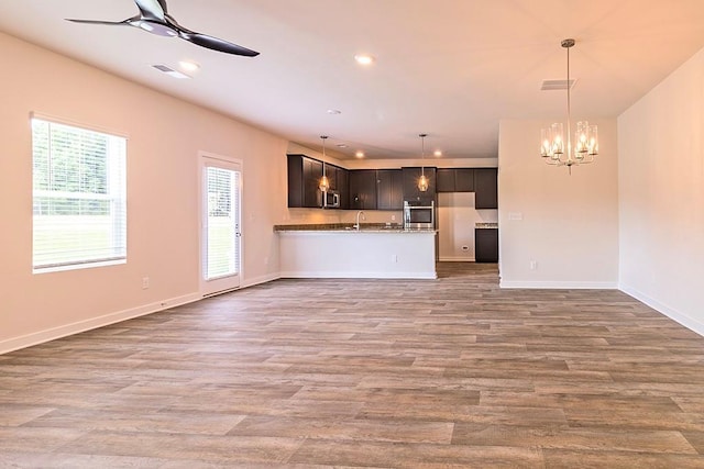 unfurnished living room featuring recessed lighting, visible vents, wood finished floors, and ceiling fan with notable chandelier