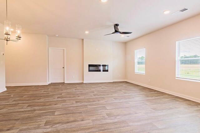 unfurnished living room with recessed lighting, light wood-style flooring, visible vents, and a glass covered fireplace