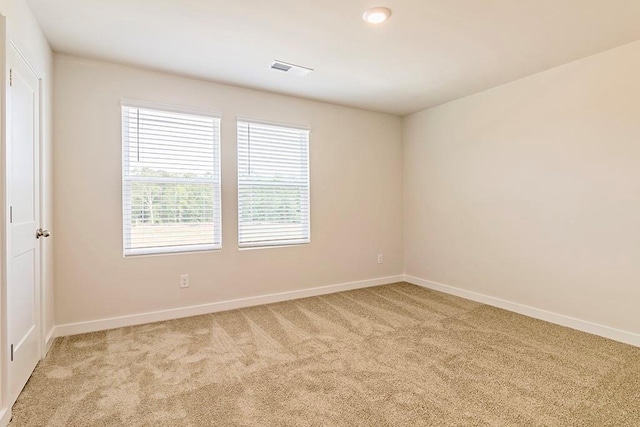 spare room featuring visible vents, baseboards, and light colored carpet