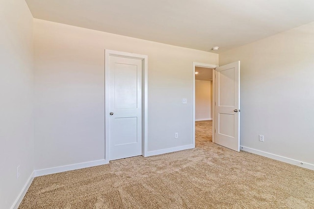 unfurnished bedroom featuring baseboards and light colored carpet