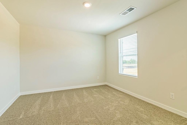 empty room featuring baseboards, visible vents, and light colored carpet