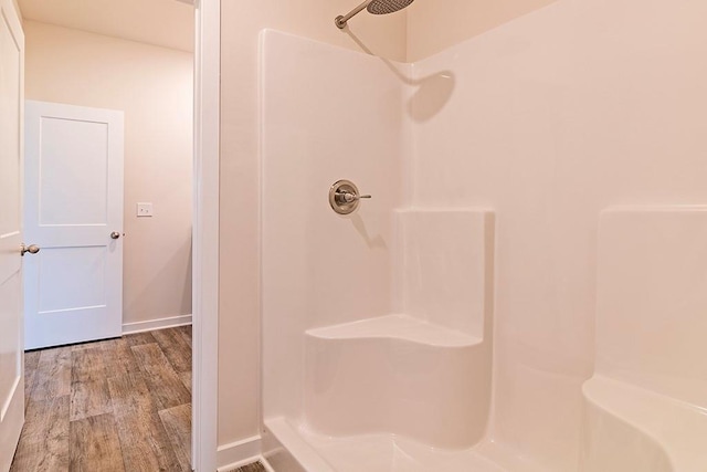 full bath featuring baseboards, walk in shower, and wood finished floors