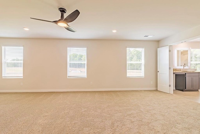 spare room with ceiling fan, baseboards, a wealth of natural light, and light colored carpet