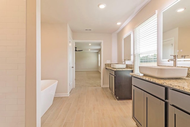 bathroom with a freestanding bath, two vanities, a sink, and visible vents