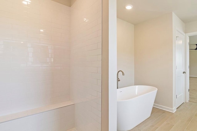 full bath with recessed lighting, a soaking tub, wood finish floors, and baseboards