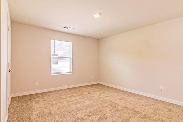 empty room with baseboards, visible vents, and light colored carpet