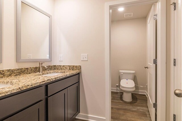 bathroom featuring toilet, baseboards, wood finished floors, and vanity