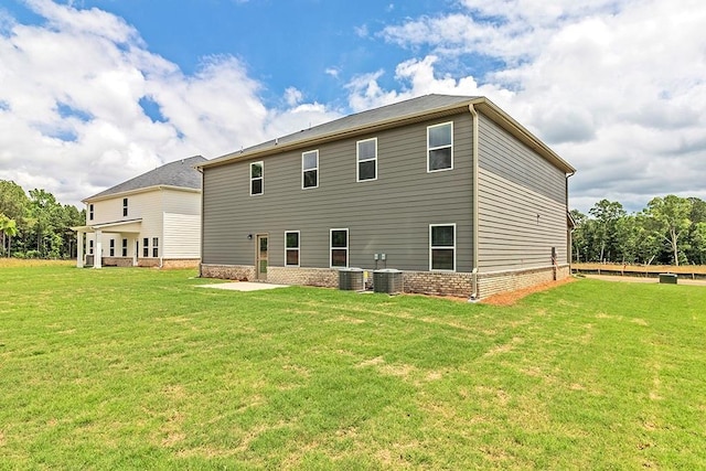 rear view of property featuring cooling unit, brick siding, and a yard