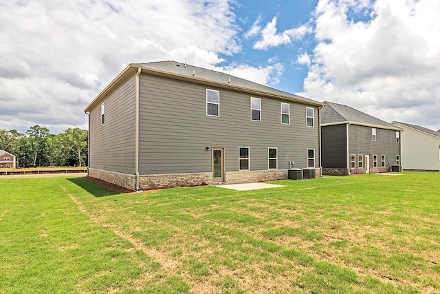 rear view of house featuring a patio area, a lawn, brick siding, and central air condition unit