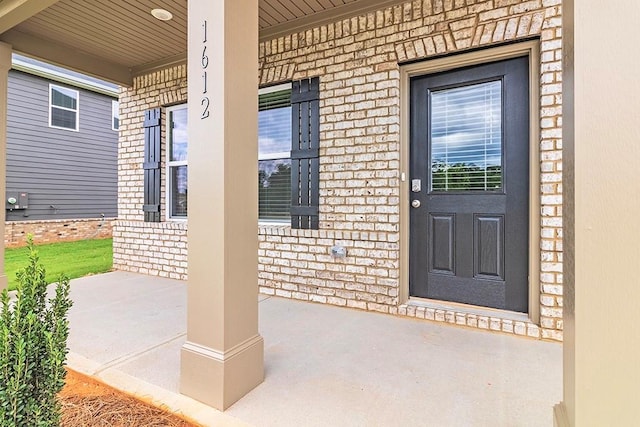 entrance to property with covered porch and brick siding