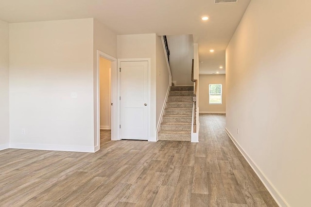 interior space featuring light wood-type flooring, stairs, and baseboards