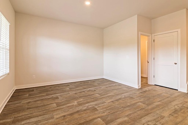 spare room with recessed lighting, wood finished floors, and baseboards