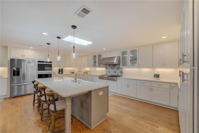 kitchen with stainless steel appliances, white cabinetry, extractor fan, sink, and decorative light fixtures