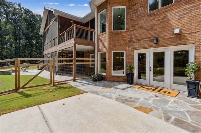 rear view of house featuring a balcony, a lawn, a patio, and french doors