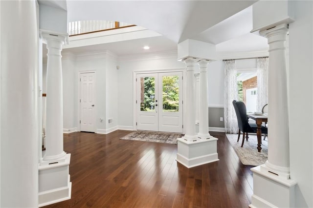 foyer entrance featuring dark wood-type flooring, ornamental molding, french doors, and ornate columns