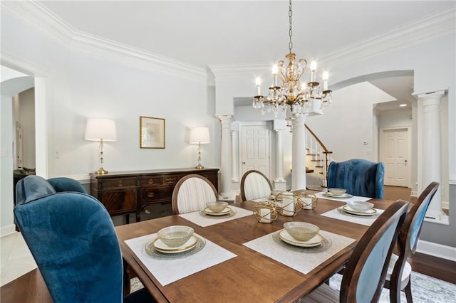 dining area with light hardwood / wood-style flooring, ornamental molding, a notable chandelier, and ornate columns