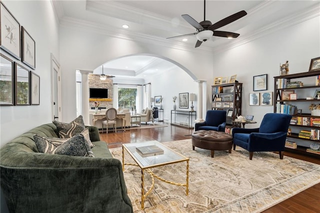 interior space featuring crown molding, decorative columns, a tray ceiling, wood-type flooring, and ceiling fan