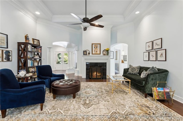 living room featuring hardwood / wood-style floors, ceiling fan, a tiled fireplace, and crown molding