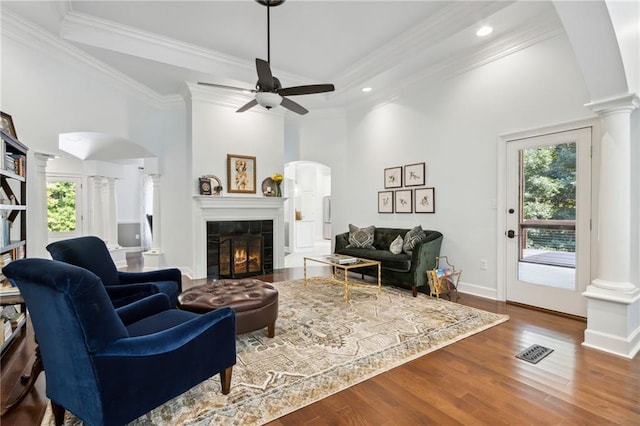 living room with plenty of natural light, ornate columns, ceiling fan, and a tile fireplace