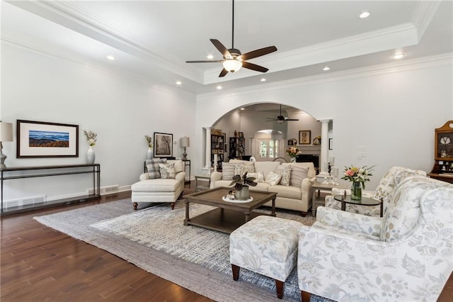 living room with ornamental molding, a raised ceiling, ceiling fan, and dark hardwood / wood-style floors