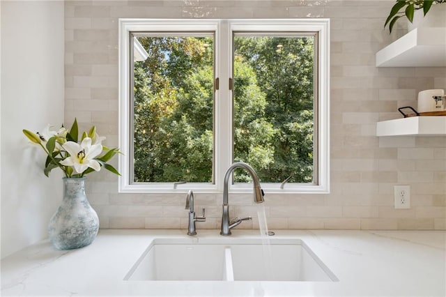 kitchen featuring light stone countertops, plenty of natural light, and sink