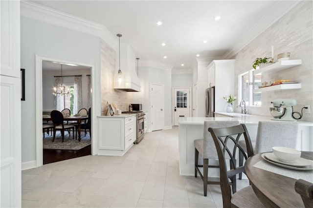 kitchen with ornamental molding, stainless steel appliances, decorative light fixtures, kitchen peninsula, and white cabinets