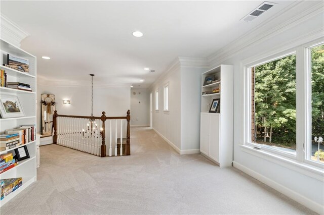 hallway featuring crown molding, light colored carpet, and a notable chandelier