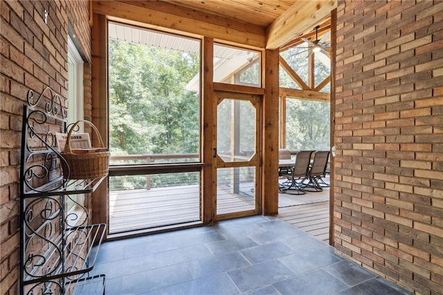 doorway to outside featuring brick wall, vaulted ceiling with beams, ceiling fan, and hardwood / wood-style flooring