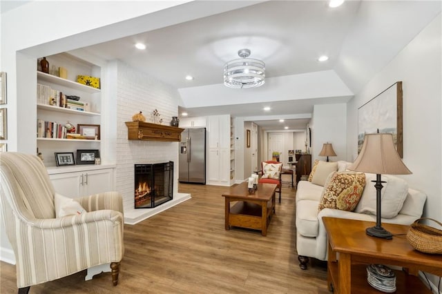 living room with a fireplace, vaulted ceiling, and light wood-type flooring