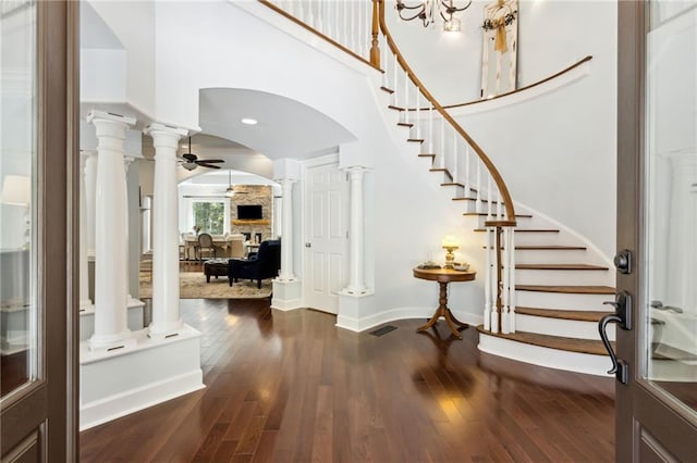 entryway featuring ceiling fan with notable chandelier, dark hardwood / wood-style flooring, and ornate columns